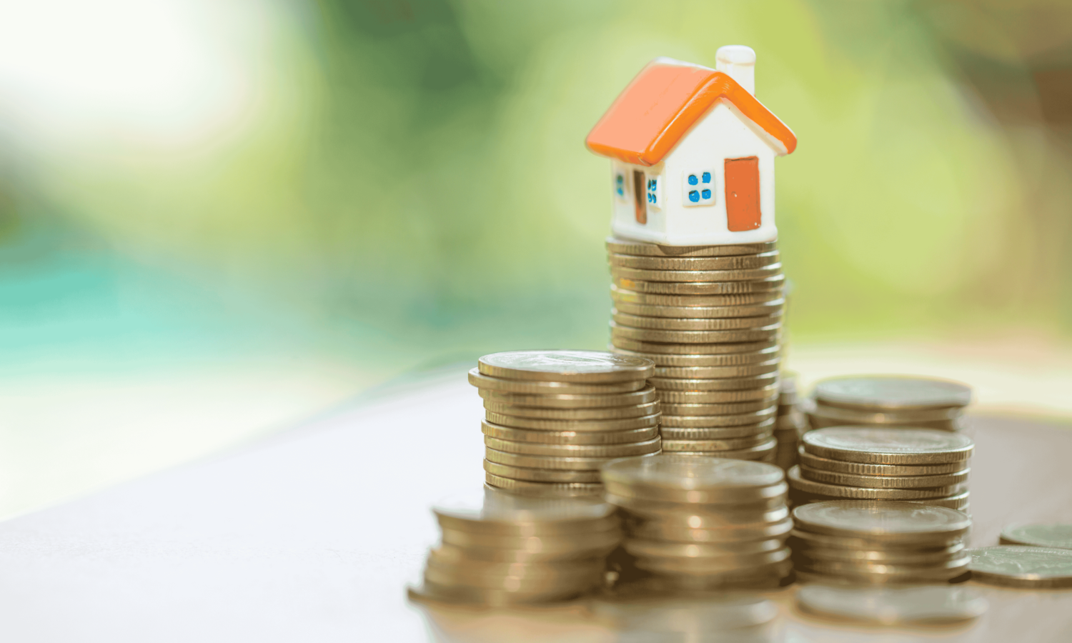 A cast model of a house is perched on top of seven stacks of coins representing seven measures in the Autumn Budget that property owners should watch out for on November 26 2025