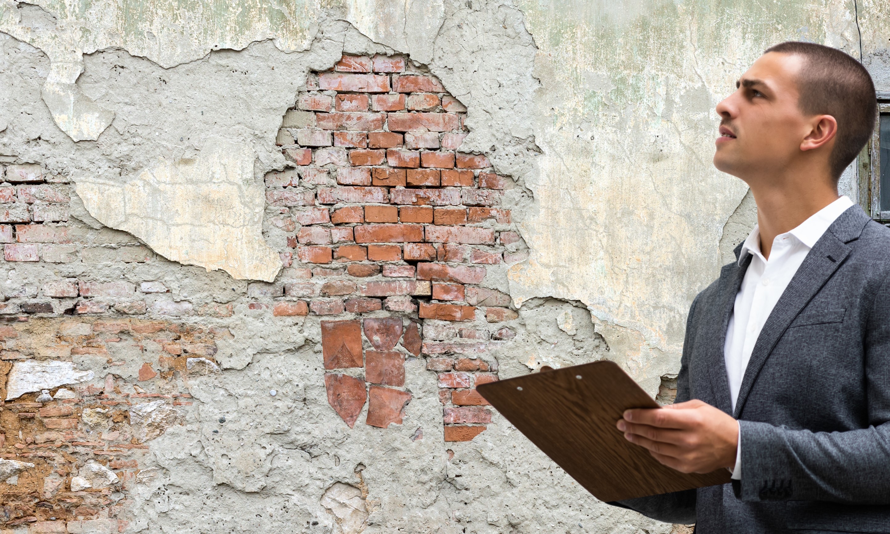 What Survey is the Right Survey? A Surveyor inspects an old brick wall with cracked plaster